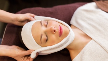 woman having face massage with towel at spa